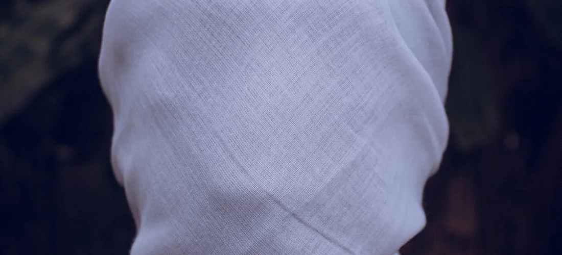 White shroud covering a body, symbolizing ghusl and Islamic funeral rites.