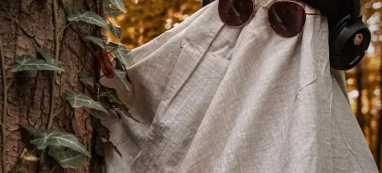 Figure draped in a white burial shroud near a tree, symbolizing Islamic funeral practices for women