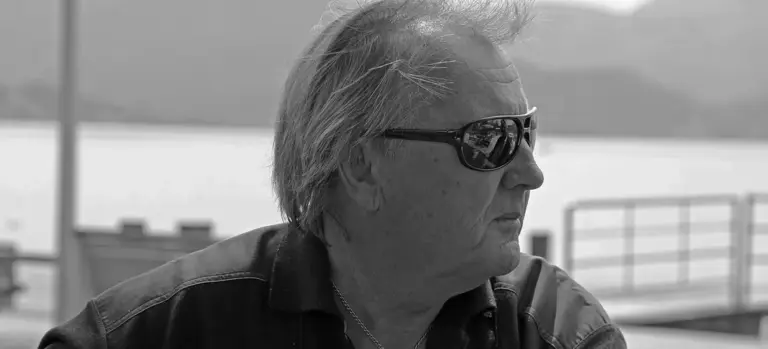 Side profile of a man wearing sunglasses outdoors.