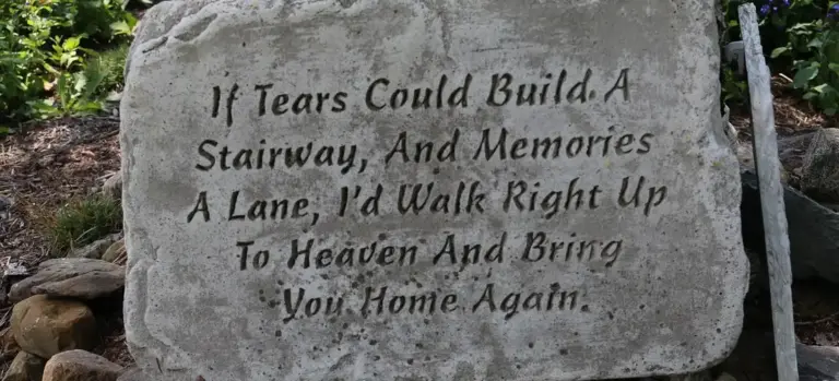 A carved stone memorial with the inscription: 'If tears could build a stairway, And memories a lane, I'd walk right up to heaven and bring you home again.'
