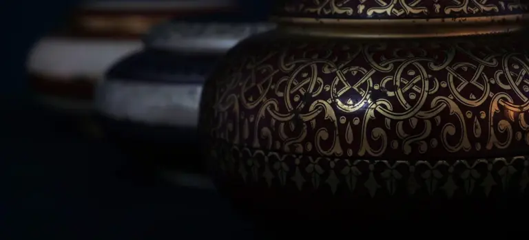 Close-up of decorative cremation urns with intricate gold patterns, representing pet memorial keepsakes.