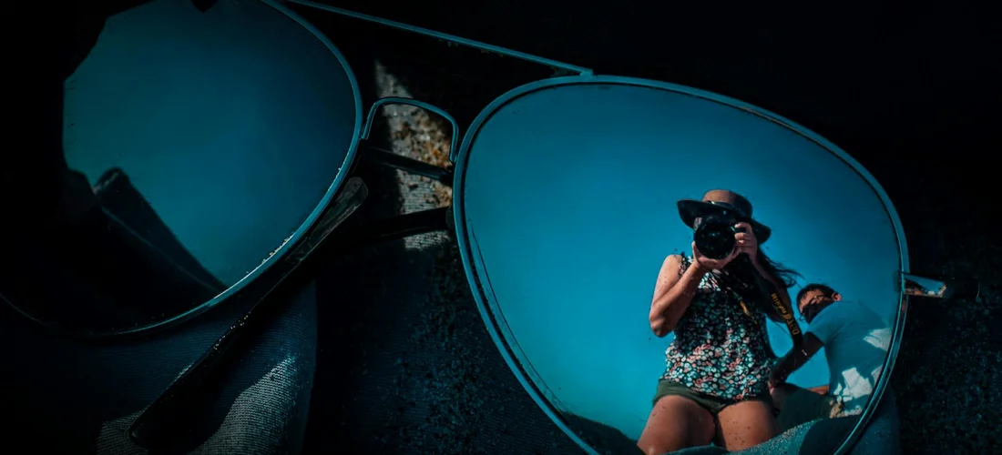 Sunglasses reflecting a photographer taking a picture, illustrating contemplation of eyewear at a funeral
